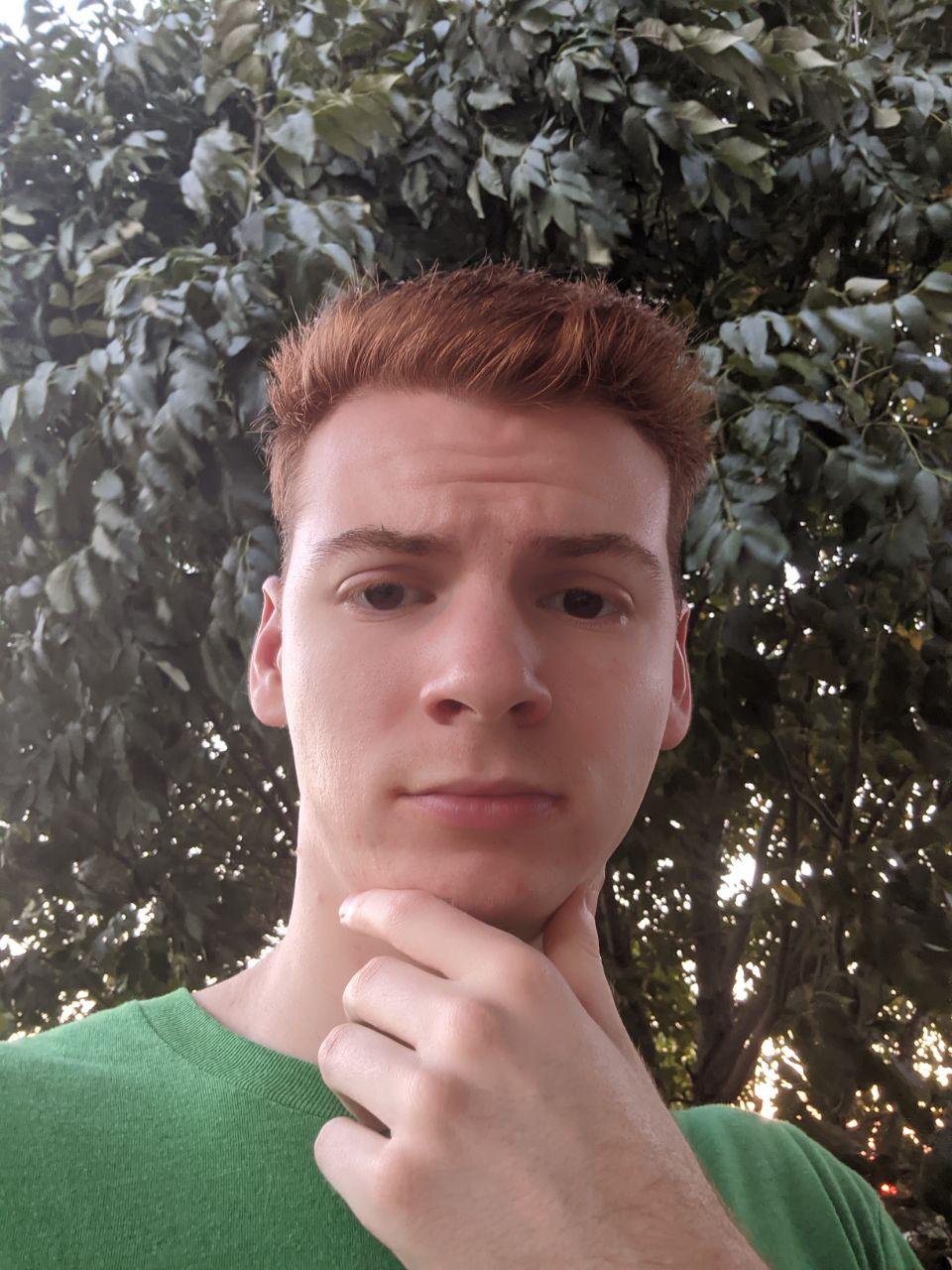 Matthew with hand on chin next to a swaying tree